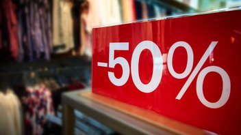 Gros plan sur une pancarte de soldes indiquant "-50%" dans une boutique de vêtements.